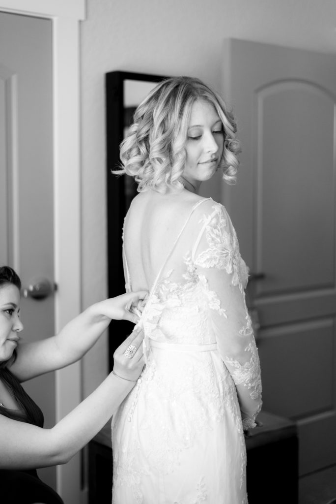 Bridesmaid helping bride get ready. Photo by Black Tie & Co. www.btcweddings.com