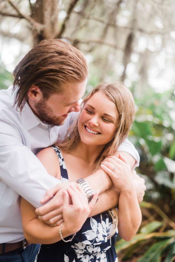 Bride smiles at groom during engagement photo in front of the Bennett House,  Alpine Groves Park. in Jacksonville Florida  Photo By Black Tie & Co. www.btcweddings.com