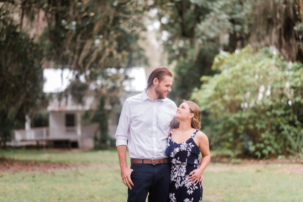 couple looking at each other in front of the Bennett House,  Alpine Groves Park for engagement photos Photo By Black Tie & Co. www.btcweddings.com