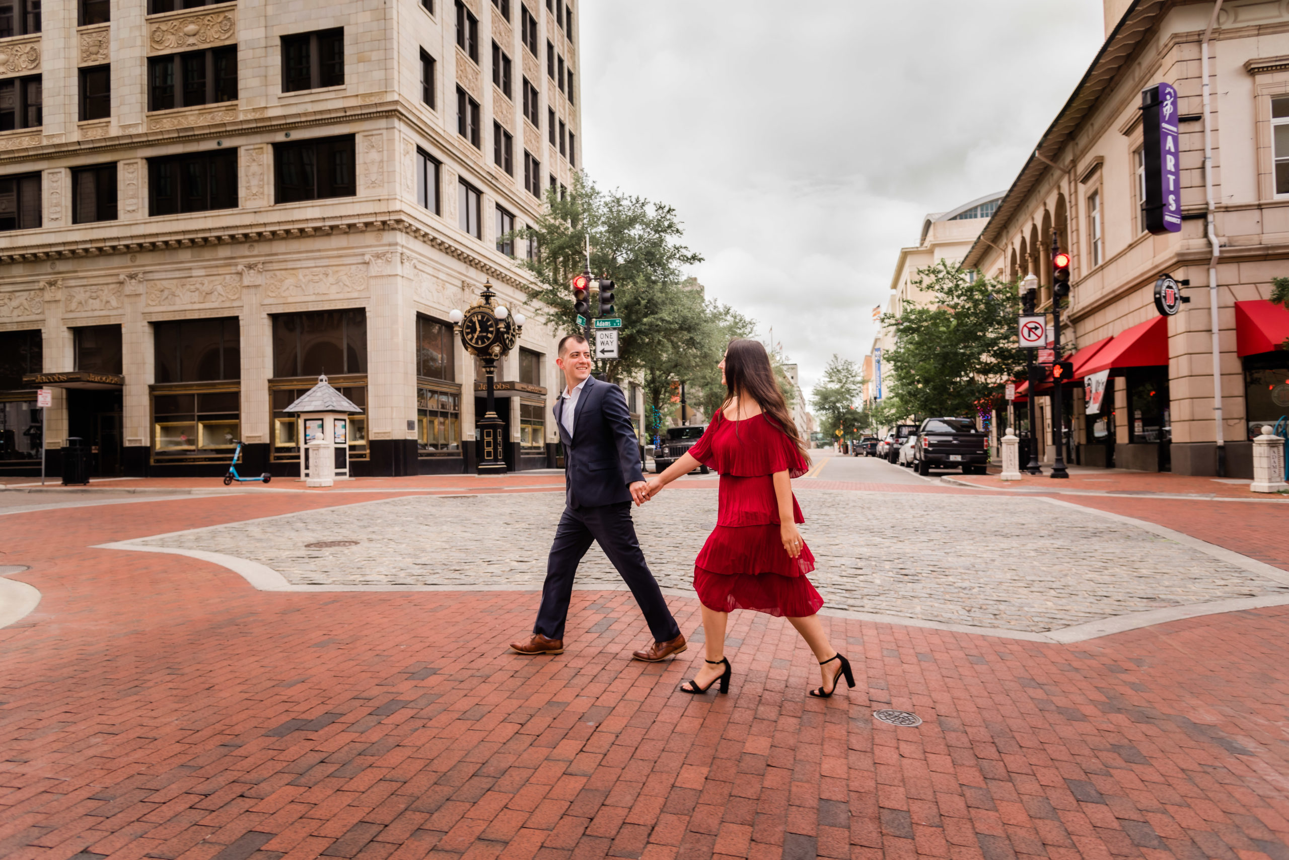 Downton Jacksonville Engagement photos. downtown, couple walks across street holding hands.